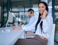 Its not a job well done until youre smiling. a young woman using a headset and computer in a modern office. Royalty Free Stock Photo