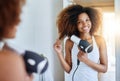 Its one of my must-have beauty tools. Portrait of an attractive young woman drying her hair with a hairdryer at home. Royalty Free Stock Photo