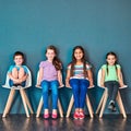 Its our turn now. Studio portrait of a diverse group of kids sitting on chairs in a line against a blue background. Royalty Free Stock Photo