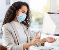 Its a precaution we call have to take. a young businesswoman spraying sanitizer on her hands while working in an office.