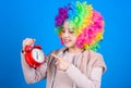 Its resting time. Happy little girl with colorful wig hair pointing at alarm clock for the exact time. Time concept Royalty Free Stock Photo
