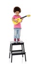 Its a serious game, this show business thing. Studio shot of a cute little girl playing with her toy guitar against a Royalty Free Stock Photo