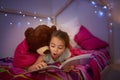 Its a story full of wonderful surprises. Cropped shot of a little girl reading a book in bed with her teddybear. Royalty Free Stock Photo