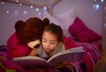 Its a story to spark the sweetest of dreams. a little girl reading a book in bed with her teddybear. Royalty Free Stock Photo