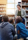 Its storytime at school. a teacher reading to a group of elementary school kids in the library. Royalty Free Stock Photo