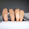 Its Sunday, put your laziest foot forward. a couples feet poking out from under the bed sheets. Royalty Free Stock Photo