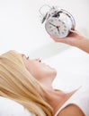 Its that time already. A young woman looking at her alarm clock in the morning. Royalty Free Stock Photo