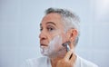 Its time for the beard to go. a mature man shaving his face in a bathroom at home. Royalty Free Stock Photo