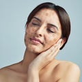 Its time to even that uneven skin tone. a young woman touching her face against a grey background. Royalty Free Stock Photo