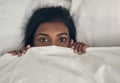 Its too cold to leave bed today. Portrait of a playful young woman hiding under the covers in a bed.