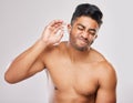 Its the weirdest feeling. a young man cleaning his ears against a grey background. Royalty Free Stock Photo