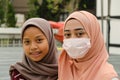 Two girls in hijab, one of them wearing a mask