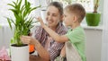 ittle boy looking at mother watering and taking care of domestic plants. Concept of gardening, hobby, home planting. Royalty Free Stock Photo