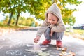 Ittle boy of 3-5 years old, sits on pavement draws, drawings with colorful crayons, creativity of children, parenting Royalty Free Stock Photo