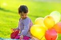 Ittle girl sitting on the grass with balloons in spring