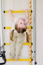 Ittle girl hangs on the stairs upside down Royalty Free Stock Photo