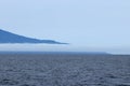 Iturup Island volcanoes on foggy horizon. The Sea of Okhotsk, Kuril Islands, Russia, claimed by Japan.