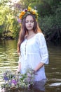 Ivan`s day. A girl in white robes is throwing a wreath down the river. Vertical portrait