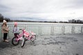 Ivano-Frankivsk, Ukraine - March, 2023: Girls with pink rose bycicle near lake