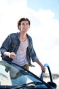 Ive reached my destination at last. Happy young man holding a cellphone and leaning on the roof of his car while smiling Royalty Free Stock Photo