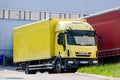 Iveco EuroCargo 180E25 yellow truck in front of depot