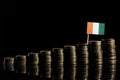 Ivorian flag with lot of coins on black