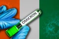 Ivory-Coast outbreak of omicron variant. Hand holds a test tube with covid-19 virus omicron in front of Ivory-Coast flag