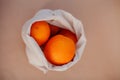ivory cotton fruit bag filled with oranges on a paper background. environmental protection concept, zero waste, conscious a