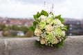 Ivory and green wedding bouquet of roses and carnation flowers on the city background