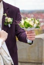 Ivory and green wedding bouquet of roses and carnation flowers in the hand of the groom