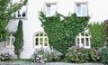 Ivy covered entrance to white painted brick house with beautiful flower garden and wreath and arched windows Royalty Free Stock Photo