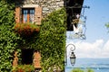 Ivy Covered Stone House with Red Flowers, Boats and Lake on a Sunny Day. Royalty Free Stock Photo