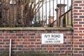 Ivy Road Leading to Laurel Close Street Sign against Brick Wall