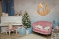 Christmas, New Year celebration. Pink sofa, fir-tree, piano, wooden picture with reindeers.