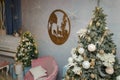 Izmail, Ukraine. December 2020. Christmas, New Year celebration. Pink sofa, two fir-trees, piano, wooden picture with reindeers.