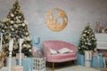 Christmas and New Year celebration. Pink sofa, two fir-trees and wooden picture with reindeers