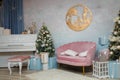 Izmail, Ukraine. December 2020. Festive decorated fir-tree in living room with piano, pink sofa and wrapped Christmas gifts. Royalty Free Stock Photo