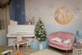 Room decorated for Christmas, New Year celebration. Pink sofa, piano, fir-tree, wooden picture Royalty Free Stock Photo