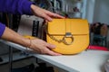 Izmail, Ukraine. May 2021. Female hands holding yellow rounded pouch, clutch with chain handle, Guess brand handbag