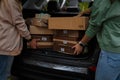 Two women taking carton packages, parcels out of car. Close up only hands, back view