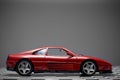 Side view of a Red toy Ferrari 348TB sports car close up product shot on a chequered ground and gray background Royalty Free Stock Photo