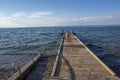 Izola / SLOVENIA - June 23, 2018: People enjoying great summer day on stone beach. Boy running on wooden pier