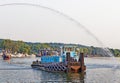 Tugboat arriving harbor event under water spray arc