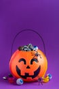 Jack-o-lantern bag full of candy on purple background with copy space,  vertical Royalty Free Stock Photo