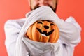Jack o lantern with smile in guys hands, close up. Halloween decorations concept. Man holds decor item on red background Royalty Free Stock Photo