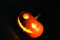 Jack-o-lanterns, tilted camera, with a evil face on the black background Royalty Free Stock Photo