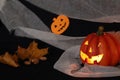 Jack pumpkin head on a dark background with gauze and decorations in the form of paper-cut bats and pumpkins. Burning candles.