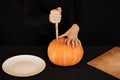 Jack`s Halloween pumpkin. Girl`s hand with a knife cutting an orange pumpkin