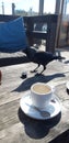 Jackdaw is steeling a cookie and drinking from coffee cream cup on beach club terrace in Noordwijk. Royalty Free Stock Photo