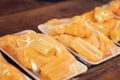 Jackfruit Artocarpus heterophyllus wrapped with plastic cover for display for sale on a wooden table market stall